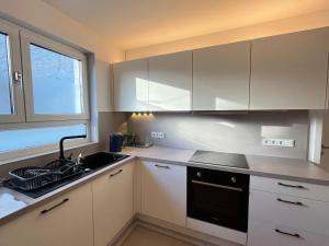 eine Küche mit weißen Schränken und einer Spüle und einem Fenster in der Unterkunft Frankfurt Messe Luxury Business Suit in Frankfurt am Main