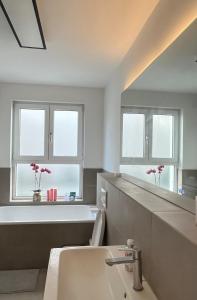 ein Badezimmer mit Waschbecken, Badewanne und Fenstern in der Unterkunft Frankfurt Messe Luxury Business Suit in Frankfurt am Main