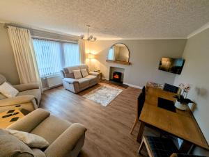 a living room with a couch and a table at Cathwill - Cosy 4 Star Cottage - Cairngorm National Park in Newtonmore