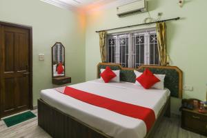 a bedroom with a large bed with red pillows at Hotel O Ma Kali Guest House in Kolkata