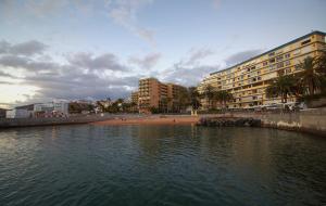 a body of water with a beach and buildings at Arguineguin Sun Beach in Arguineguín