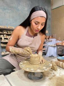 a woman making a vase on a pottery wheel at VoyAca Hotel - Alfareria in Villa de Leyva