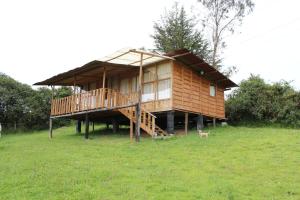 a large wooden house with a deck in a field at LINDA CABAÑA HERMOSA VISTA NATURALEZa in Suesca