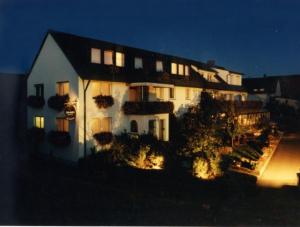 Une grande maison blanche éclairée la nuit dans l'établissement Adolphs Frühstückspension, à Bad Staffelstein