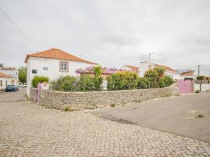 a stone wall next to a street with houses at Casa das bonecas in Pernigem