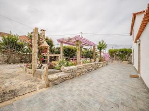 a garden with a stone wall and a pergola at Casa das bonecas in Pernigem