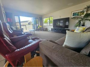 Una sala de estar con sofás y un televisor de pantalla plana. en Marina Vista, en Whangarei
