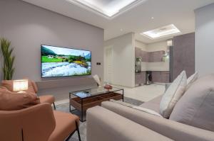 a living room with a couch and a tv on a wall at أكاريم أفينيوز Akareem Avenues in Riyadh