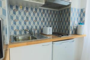 a small kitchen with a sink and blue tiles at Studio 2P Roland Garros Parc des in Boulogne-Billancourt +1 photo