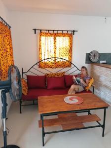 a woman sitting on a couch in a living room at Sene Centro Résidence in Cap Skirring