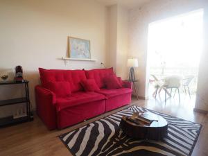 Duplex Panorâmico com vista incrível! Morro do Elefante! في كامبوس دو جورداو: أريكة حمراء في غرفة معيشة مع طاولة