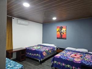 a room with two beds and a table and a painting at Hostal Mamá Derlys in Moyogalpa