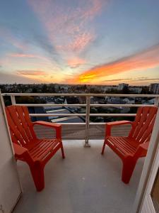 two red chairs on a balcony with a sunset at Séjour détente à Blois - Parking & Netflix inclus in Blois
