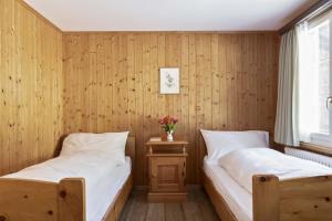 two beds in a room with wooden walls at Hotel Bad Serneus in Klosters
