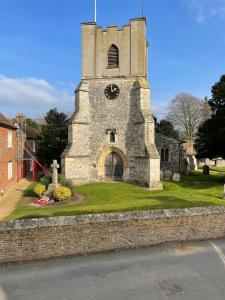 an old building with a clock tower on the grass at Happy Hinwood House, Hampshire! in Stockbridge