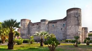 um grande castelo com palmeiras em frente em L'Albero della Vita em Catânia