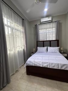 una camera con un grande letto e due finestre di Blue wave loft a Dar es Salaam