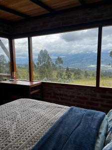 a bedroom with a bed in front of a large window at Andes Sky Lodge in Hacienda Cochasquí +17 photos