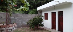 a white house with a red door and a tree at Casita del Campo in Pomancillo