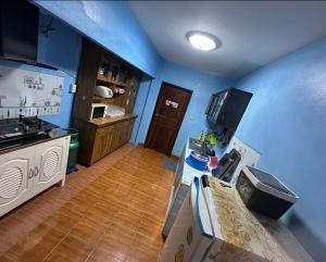 una cucina con pareti blu e pavimenti in legno e un bancone di บ้านปรินรดา poolvilla สัตหีบ a Sattahip Altre 10 foto