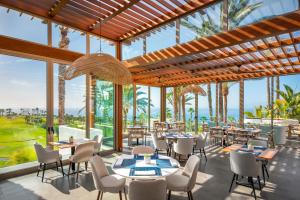 a restaurant with tables and chairs and palm trees at Las Terrazas de Abama Suites in Guía de Isora