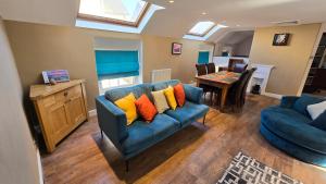 a living room with a blue couch with colorful pillows at Longden Court Mews in Buxton