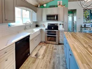 a kitchen with white cabinets and a wooden floor at Sand Piper in Rockport +22 photos