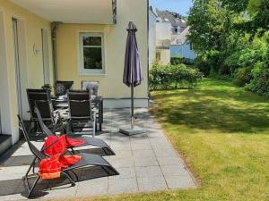 un patio con sillas, sombrilla y césped en Apartment Sonneninsel, en Zinnowitz