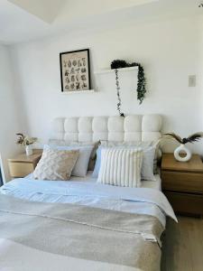una camera da letto con un grande letto bianco con cuscini di Azure Staycation by Maxan a Manila