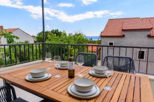 a wooden table with plates and wine glasses on a balcony at Apartments with WiFi Bol, Brac - 23862 in Bol