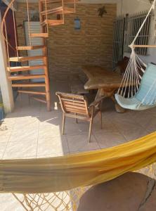 a hammock and chairs on a porch with a staircase at Quarto com Ar-condicionado há 600 metros da Praia de Setiba in Guarapari
