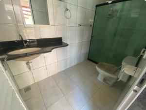 a bathroom with a toilet and a sink and a shower at Quarto com Ar-condicionado há 600 metros da Praia de Setiba in Guarapari