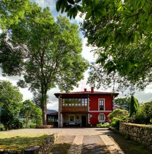una casa rossa con un albero di fronte di Hotel Rural Coviella a Coviella