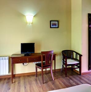 CoviellaにあるHotel Rural Coviellaのデスク、テレビ、椅子2脚が備わる客室です。