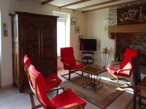 a living room with red chairs and a fireplace at Holiday Home by Kerleven Beach, France in La Forêt-Fouesnant