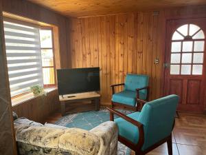 a living room with a couch and two chairs and a television at Hostal Livary Puerto Varas in Puerto Varas