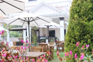 an outdoor patio with tables and umbrellas and flowers at Hotel Harmika in Kathmandu