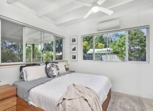 - une chambre blanche avec un lit et des fenêtres dans l'établissement Palm Springs Bungalow, à Trinity Beach