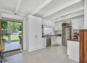 une cuisine avec des armoires blanches et des appareils en acier inoxydable dans l'établissement Palm Springs Bungalow, à Trinity Beach