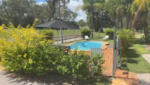 a fence around a swimming pool with an umbrella at Mt Morgan Motel & Van Park in Ulogie