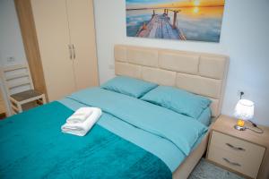 a bedroom with a bed with blue sheets and a picture at Fishta apartments Q5 32 in Velipojë