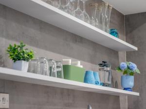 a shelf with glasses and vases on it in a kitchen at Fabulous Festival Park Home Private Parking Garden Pass the Keys in Glasgow +28 photos