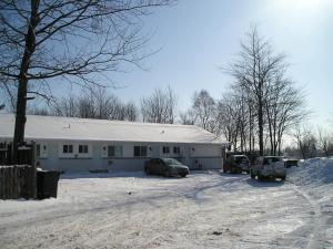 un edificio blanco con coches aparcados en la nieve en Motel Le Victo, en Victoriaville