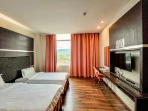 a hotel room with two beds and a flat screen tv at Courtyard Hotel 1Borneo in Kota Kinabalu