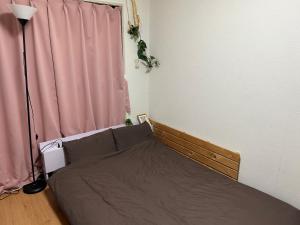 ein Schlafzimmer mit einem Bett und einem rosa Vorhang in der Unterkunft Guest House Yakuin INN in Fukuoka
