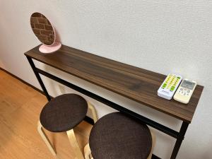 einen hölzernen Schreibtisch mit zwei Fernbedienung in der Unterkunft Guest House Yakuin INN in Fukuoka