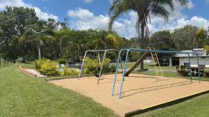 a playground in a park with a swing at Mt Morgan Motel & Van Park in Ulogie