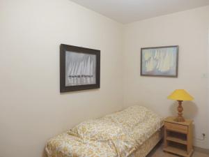 Un dormitorio con una cama y una lámpara sobre una mesa. en Maison spacieuse à 400m de la plage des Govelins, vue mer - FR-1-639-138, en Saint-Gildas-de-Rhuys