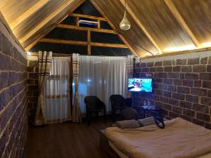 a bedroom with a bed and a tv in a brick wall at La Renada in Mawphlang