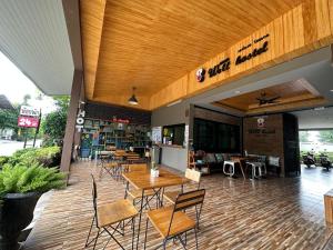ein Restaurant mit Tischen und Stühlen in einem Gebäude in der Unterkunft Warmwell Hotel in Ban Chuk Kum